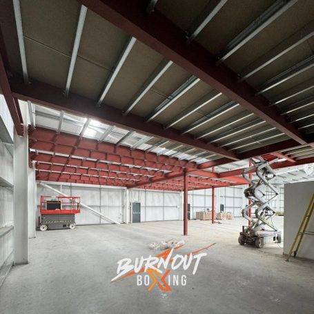 Interior of a vacant boxing gym, featuring exposed metal beams and scaffolding.